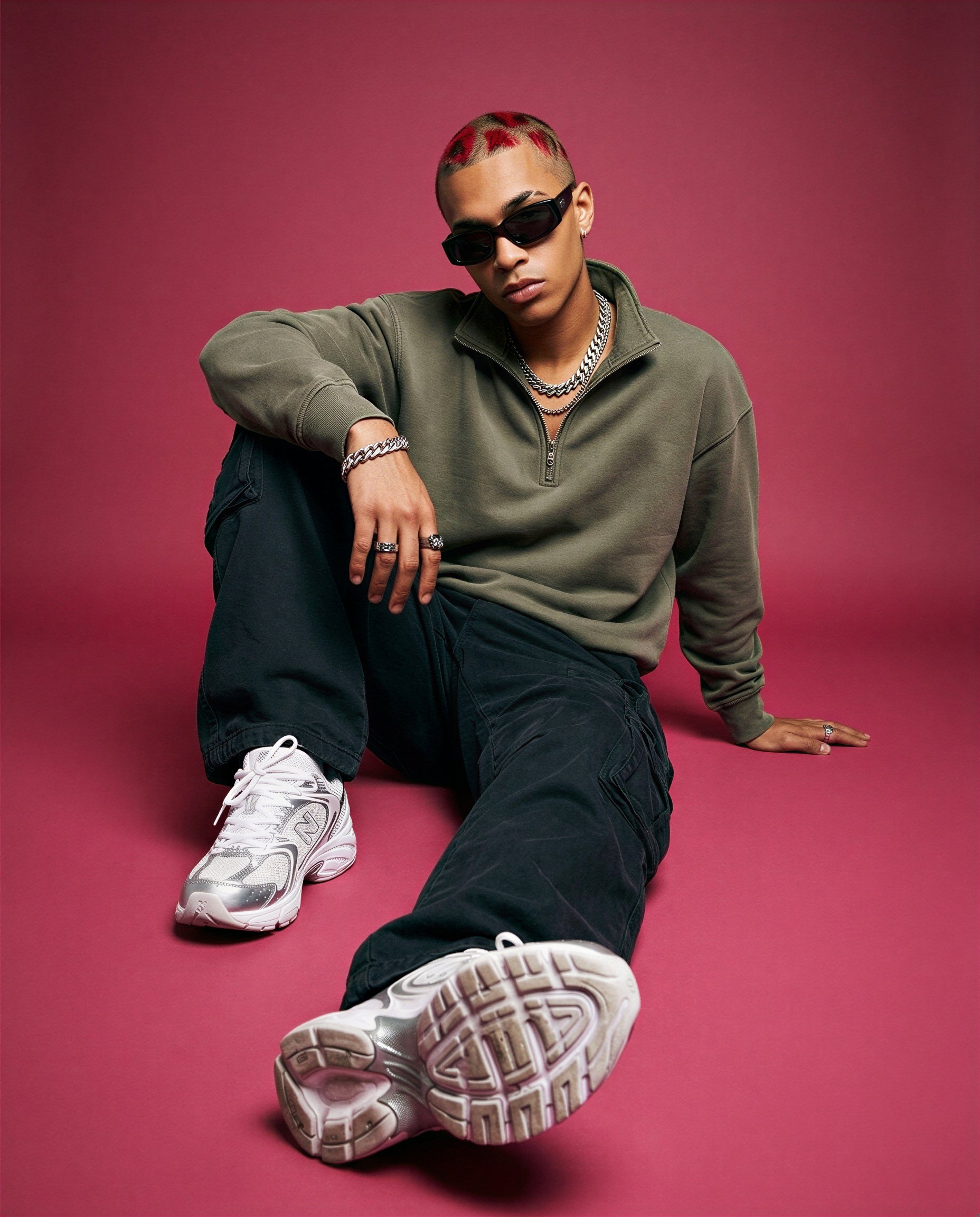 Person wearing sunglasses and the khaki Foundation Quarter Zip sweater sitting on a pink background
